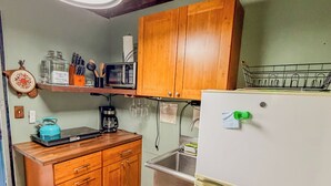 Una cocina funcional con armarios de madera, un refrigerador blanco, un microondas y un lavabo.