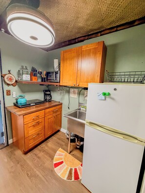 Una cocina funcional con armarios de madera, un refrigerador blanco, un microondas y un lavabo.
