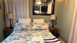 Un dormitorio con cama, dos mesitas de noche, un espejo y luces de hadas.