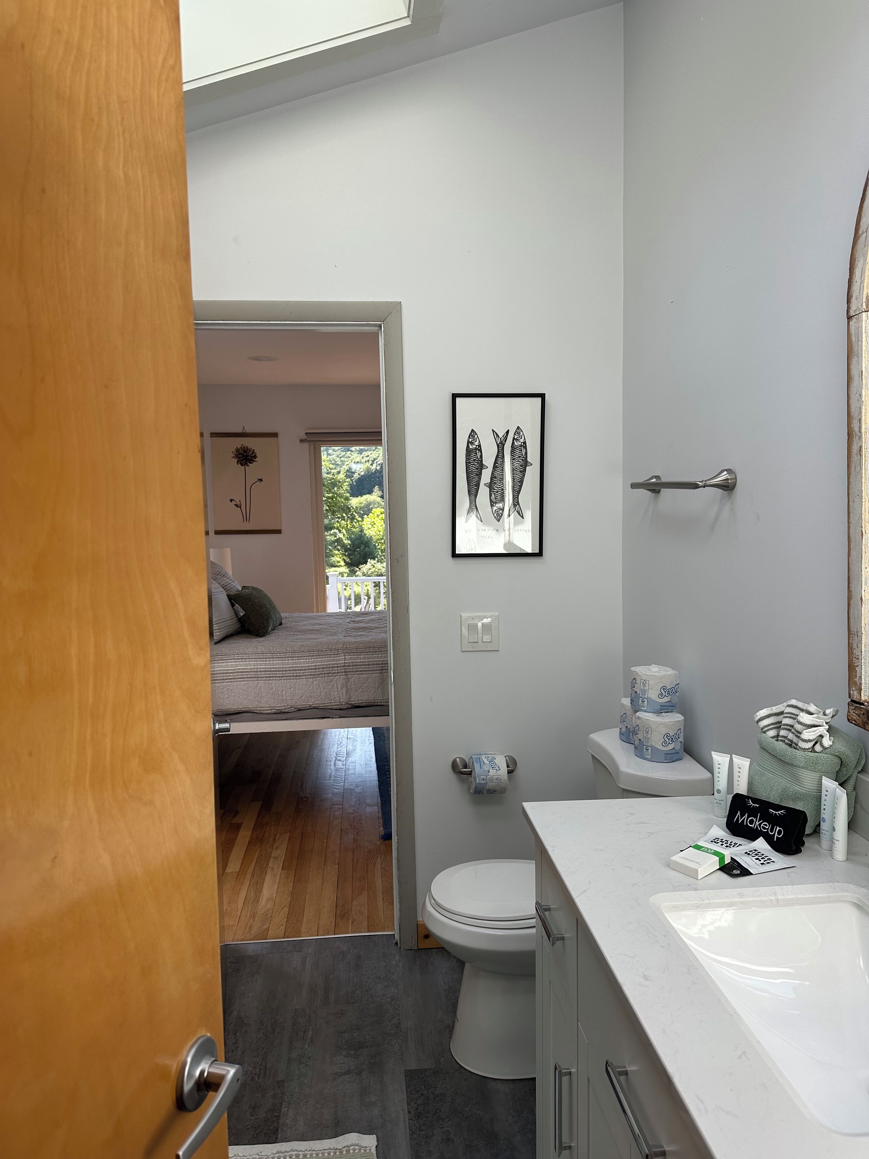 A modern bathroom with a toilet, sink, and a framed fish illustration on the wall.