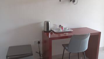Ein Hotelzimmer mit Schreibtisch, Stuhl, Wandfernseher und kleinem Kühlschrank.