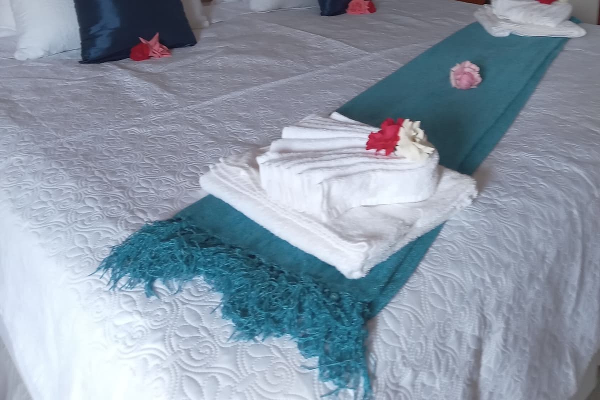 Habitació d'hotel amb un llit ben fet, un panell de capçalera de fusta i una petita taula de nit.