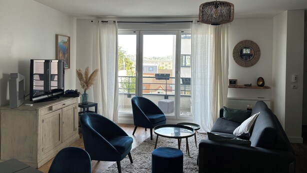 A modern living room with a TV, seating, and a view through a glass door. - Appartement Lumineux à Suresnes à Côté de Paris Vue Tour Eiffel (Suresnes)