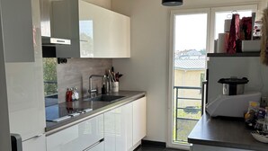 A modern kitchen with white cabinets, a black countertop, and a stainless steel trash can. - Appartement Lumineux à Suresnes à Côté de Paris Vue Tour Eiffel (Suresnes)