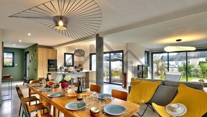 A modern dining area with a wooden table set for six, surrounded by yellow chairs. - Large, recently built architect-designed house for 12 people (Guilvinec)