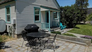 Ein weißes Haus mit Veranda, Satellitenschüssel und Grill.