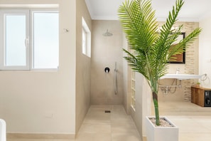 Ein modernes Badezimmer mit Dusche, Waschbecken und einer Topfpflanze.