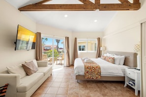 Ein Hotelzimmer mit Bett, Sofa, Fernseher und einem Balkon mit Blick.