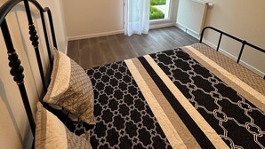 Une chambre à coucher avec un lit, une fenêtre avec des rideaux, un radiateur et un tableau accroché au mur.