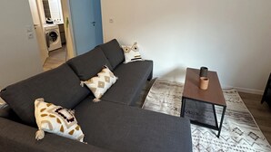 Un salon avec un canapé gris foncé, des coussins à motifs, une petite table en bois et un tapis à motifs.