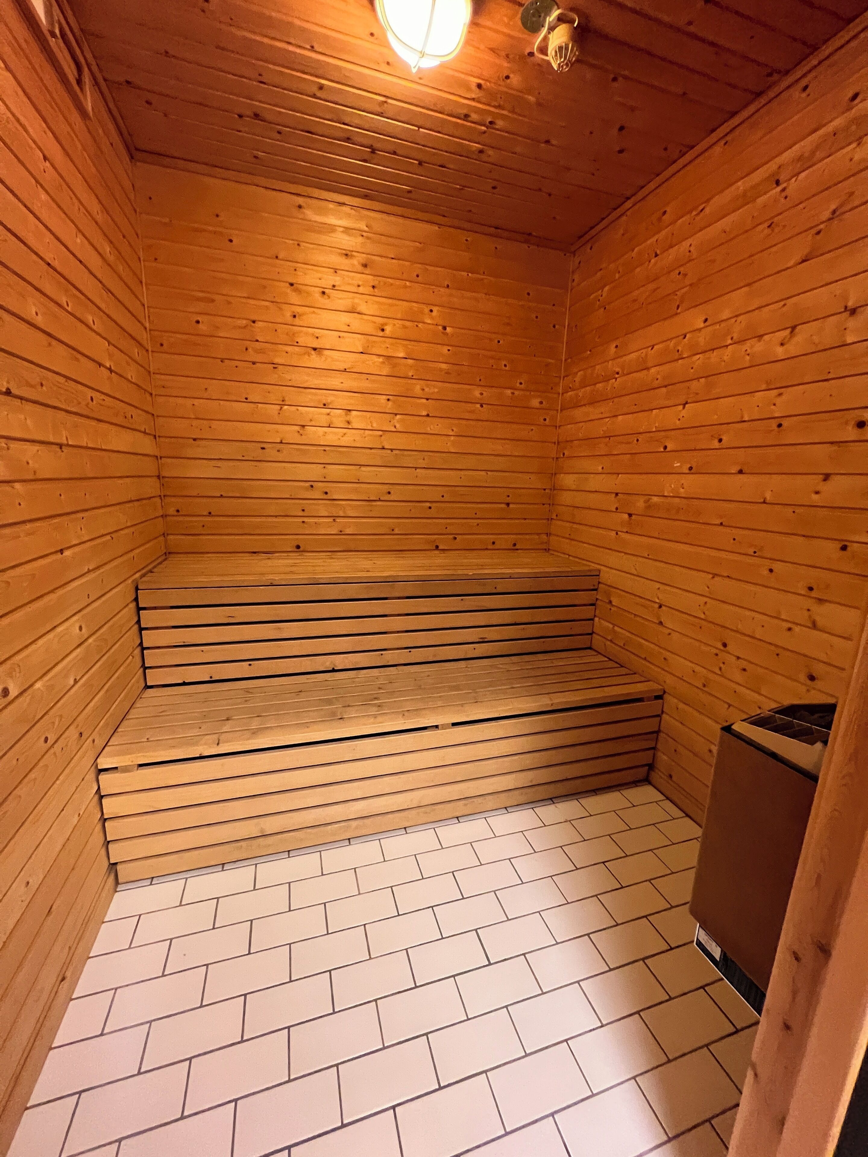 Een houten sauna met betegelde vloer en een bank.
