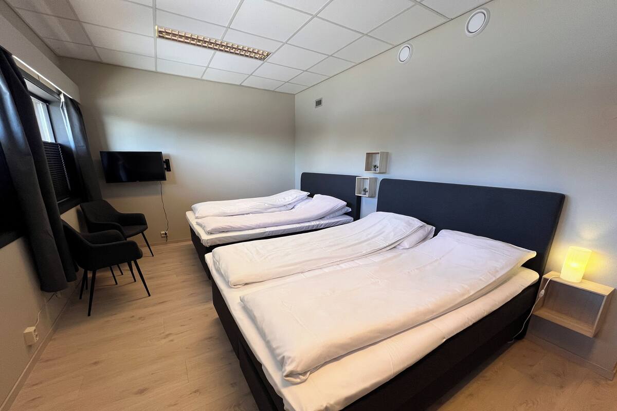 Hotellihuone, jossa on kaksi sänkyä, televisio, työpöytä ja tuoli.