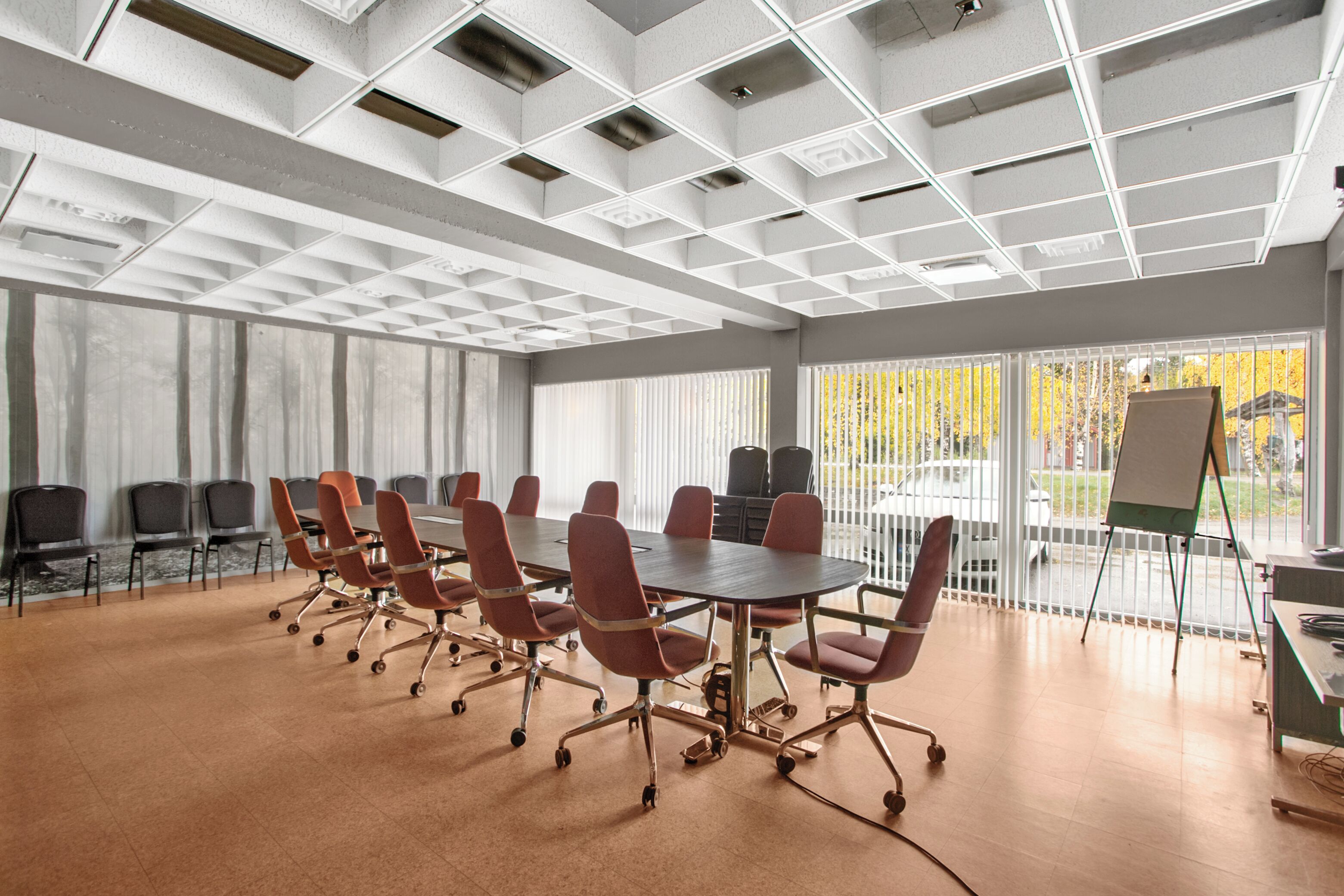 A conference room with a large table, red chairs, and a whiteboard.