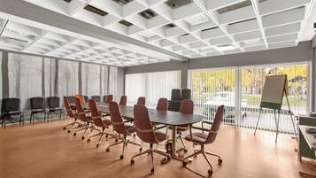 A conference room with a large table, red chairs, and a whiteboard.