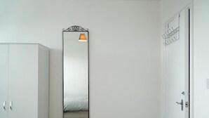 A room with a wardrobe, a door, and a mirror with a light fixture. - Clean, Spacious 2-bed Apartment in Brierley Hill (Brierley Hill)
