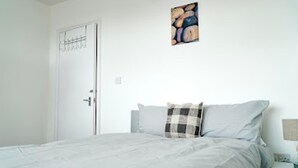 A bedroom with a bed, a nightstand, and a wall-mounted artwork. - Clean, Spacious 2-bed Apartment in Brierley Hill (Brierley Hill)