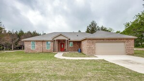 A single-story brick house with a red door, a garage, and a front yard.