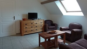 A living room with a wooden cabinet, a television, a sofa, and a table. - Gite Avec Piscine - Périgord Noir - 2 Personnes (Châtres)