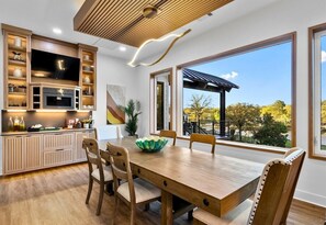 A modern kitchen with a large dining table, wooden cabinets, and a view of the outdoors. - Lakeside Luxe | Heated Pool | Dock | Sleeps 22 (Hot Springs National Park)