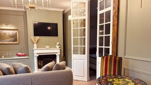 A living room with a sofa, a fireplace, a television, and a dining area with a table and chair. - Normandy Etretat (Etretat)