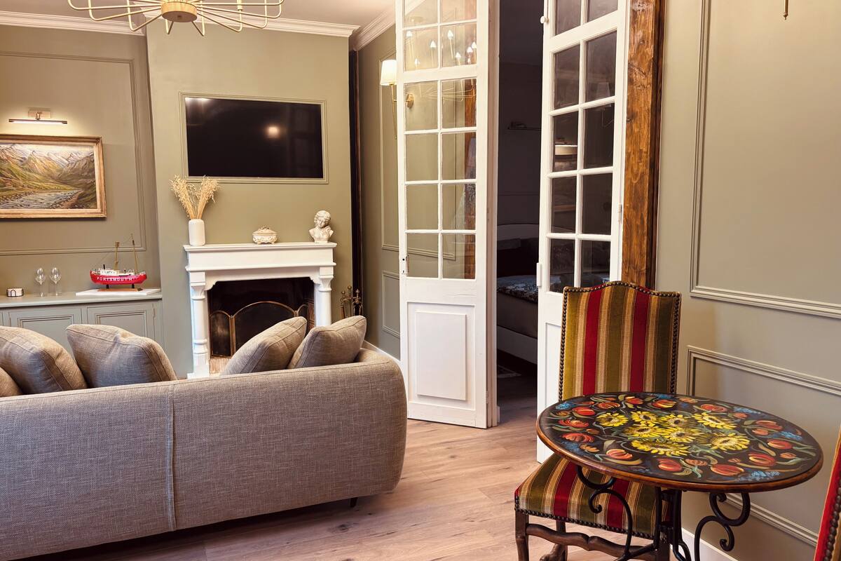A living room with a sofa, a fireplace, a television, and a dining area with a table and chair.