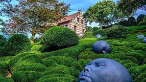 A garden with manicured hedges and a traditional building in the background. - Normandy Etretat (Etretat)
