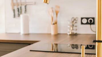 A kitchen with a black countertop, a gold faucet, and a microwave above the sink.
