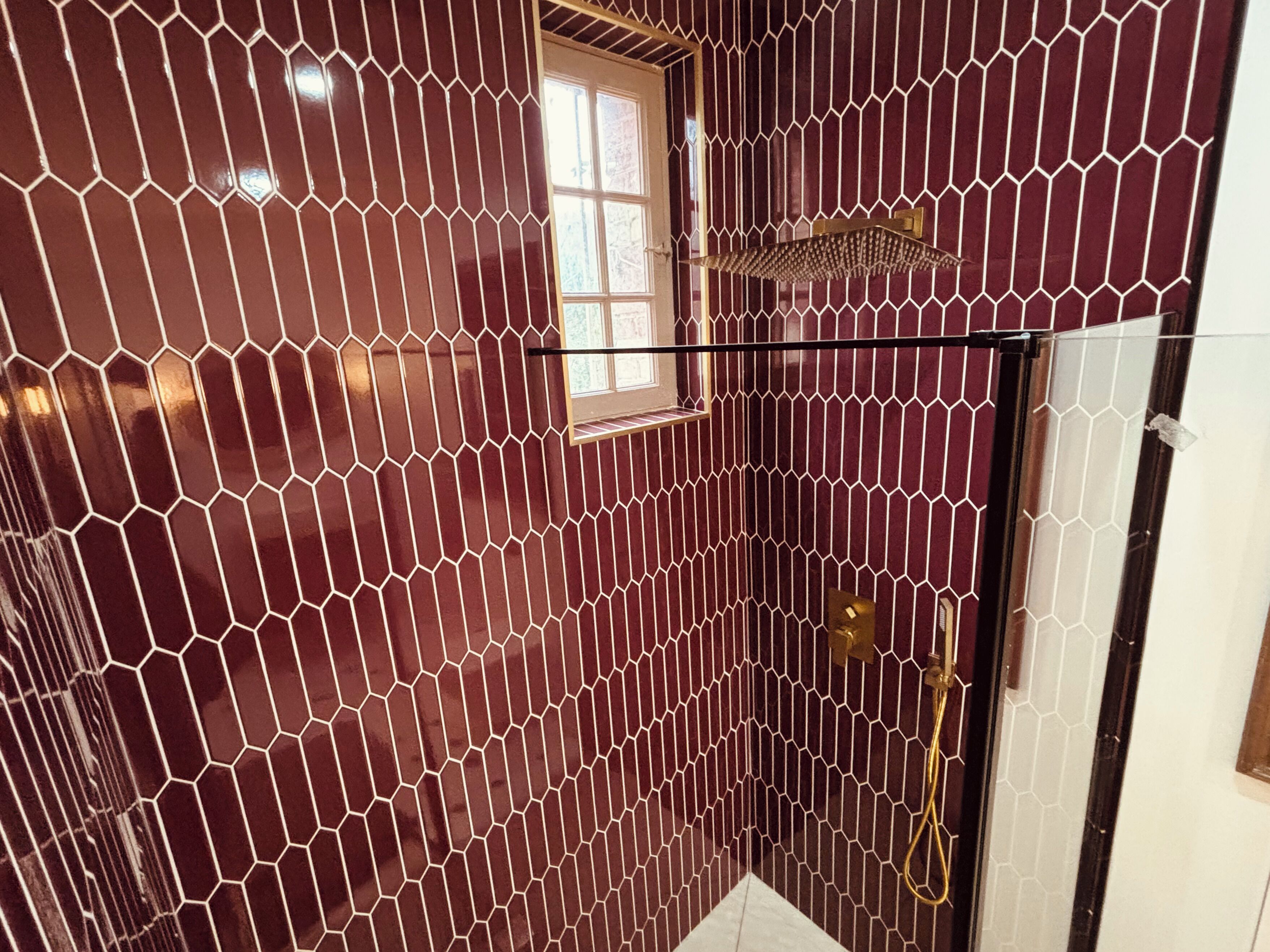 Une salle de bain avec des carreaux à motifs hexagonaux, une fenêtre et un espace douche.