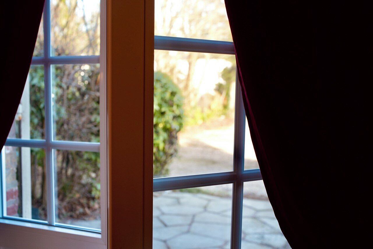 Una ventana con vista a un jardín y un camino empedrado.
