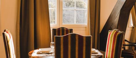 A dining area with a chandelier, striped chairs, and a table set for four.