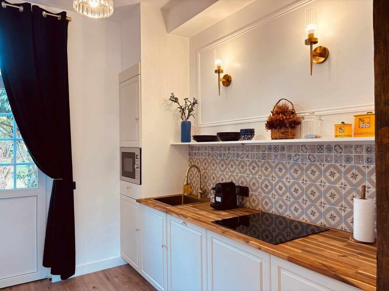 A modern kitchen with white cabinetry, a wooden countertop, a built-in oven, and a backsplash with a geometric pattern.