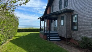 Une maison moderne dotée d’un porche abrité, d’une cheminée en briques et offrant une vue sur l’océan.
