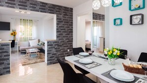 Uma sala de jantar moderna com parede de destaque em pedra, uma mesa comprida posta para refeições e arte decorativa nas paredes.
