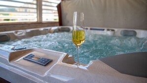 Un hidromasaje con una copa de vino y un control remoto.