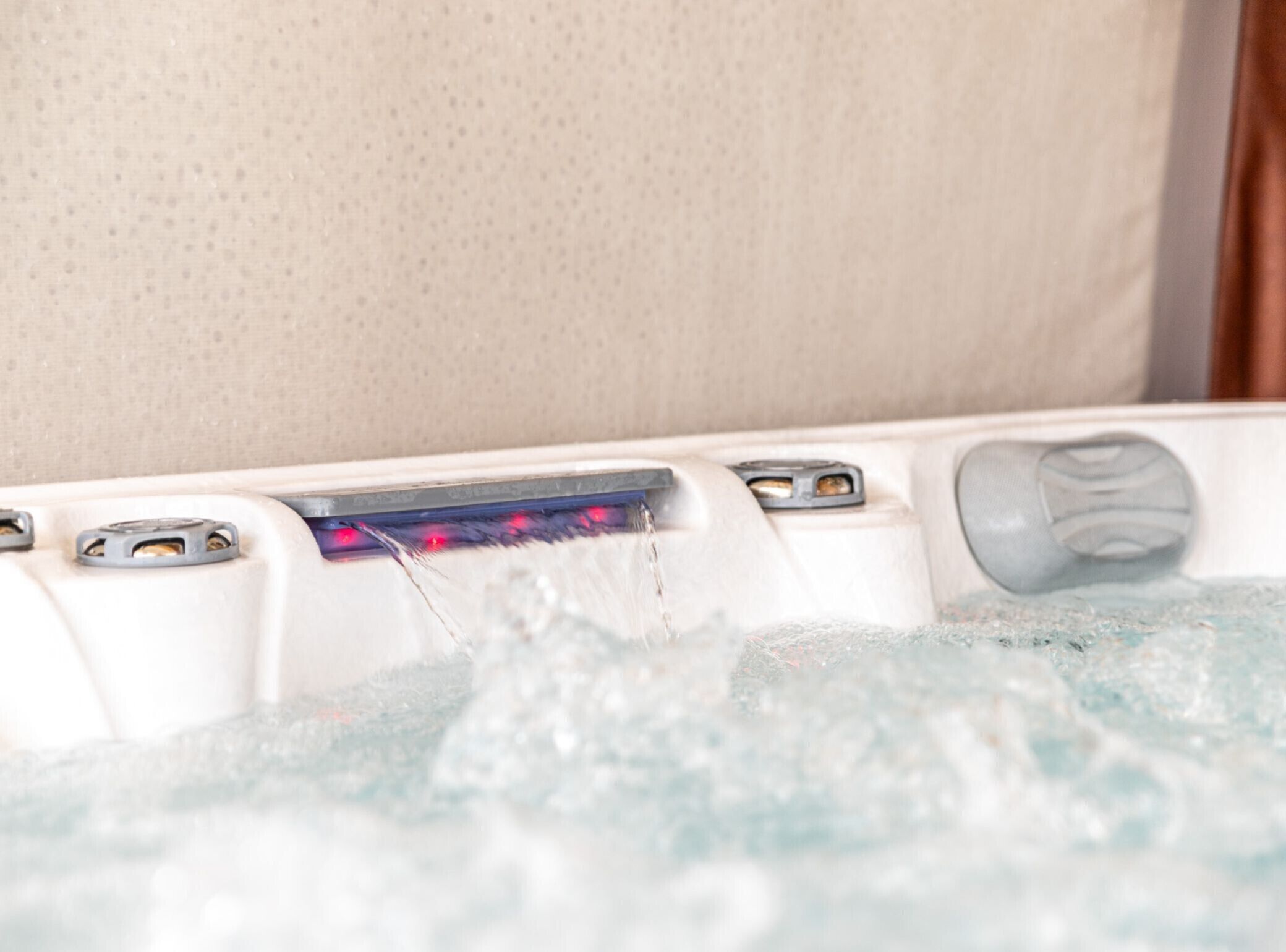 A bathtub with a control panel, a white wall, and a textured surface in the background.