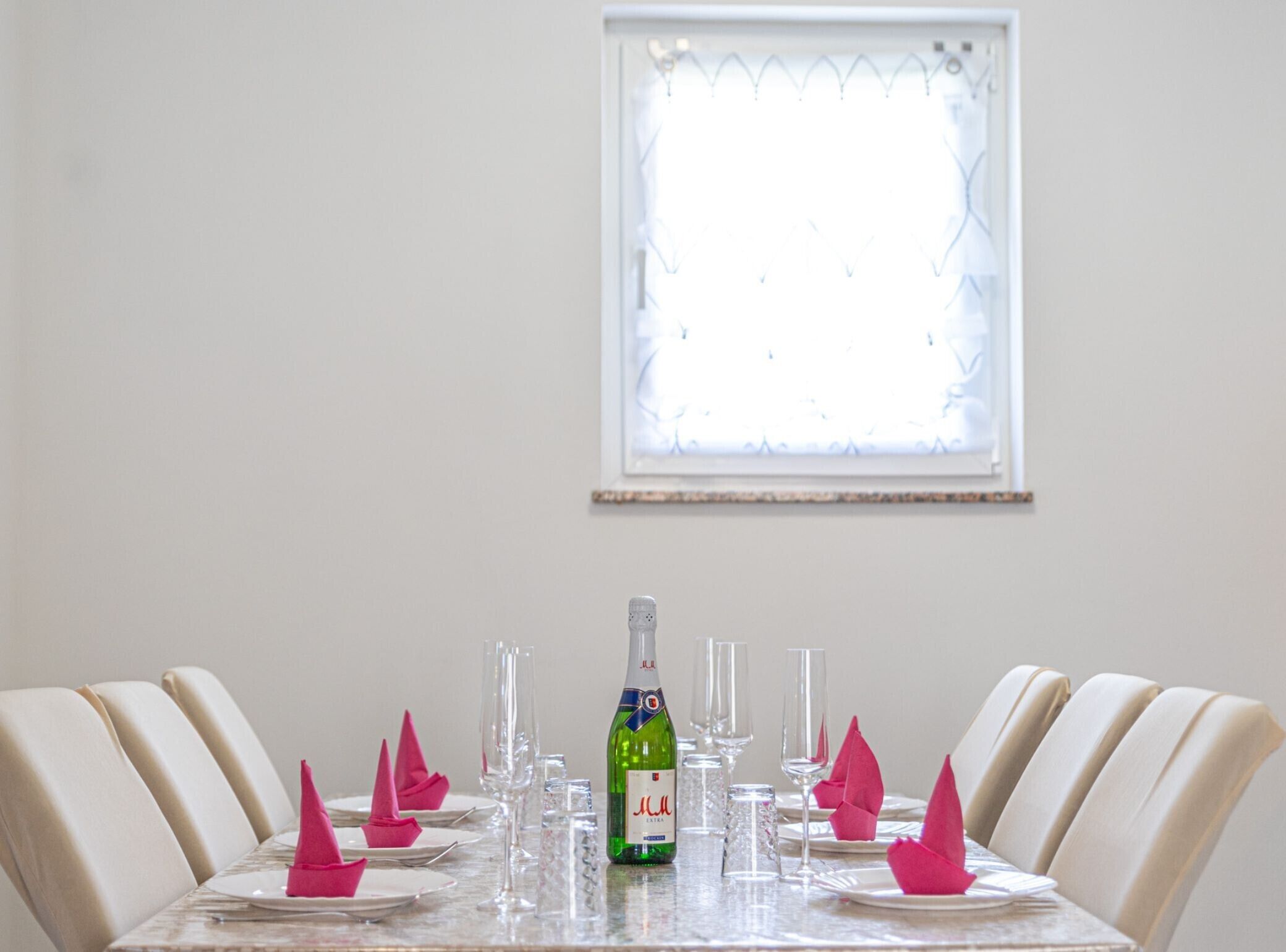 Una mesa de comedor servida con platos, vasos y una botella de agua.