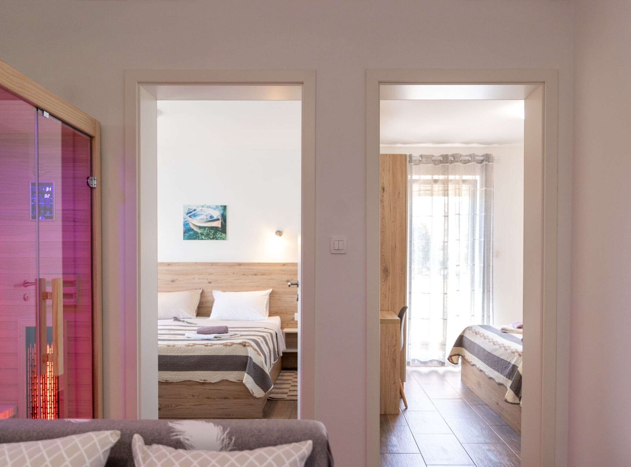 A hotel room with a bed, a bedside table, a nightstand, a wall-mounted clock, and a window with curtains.
