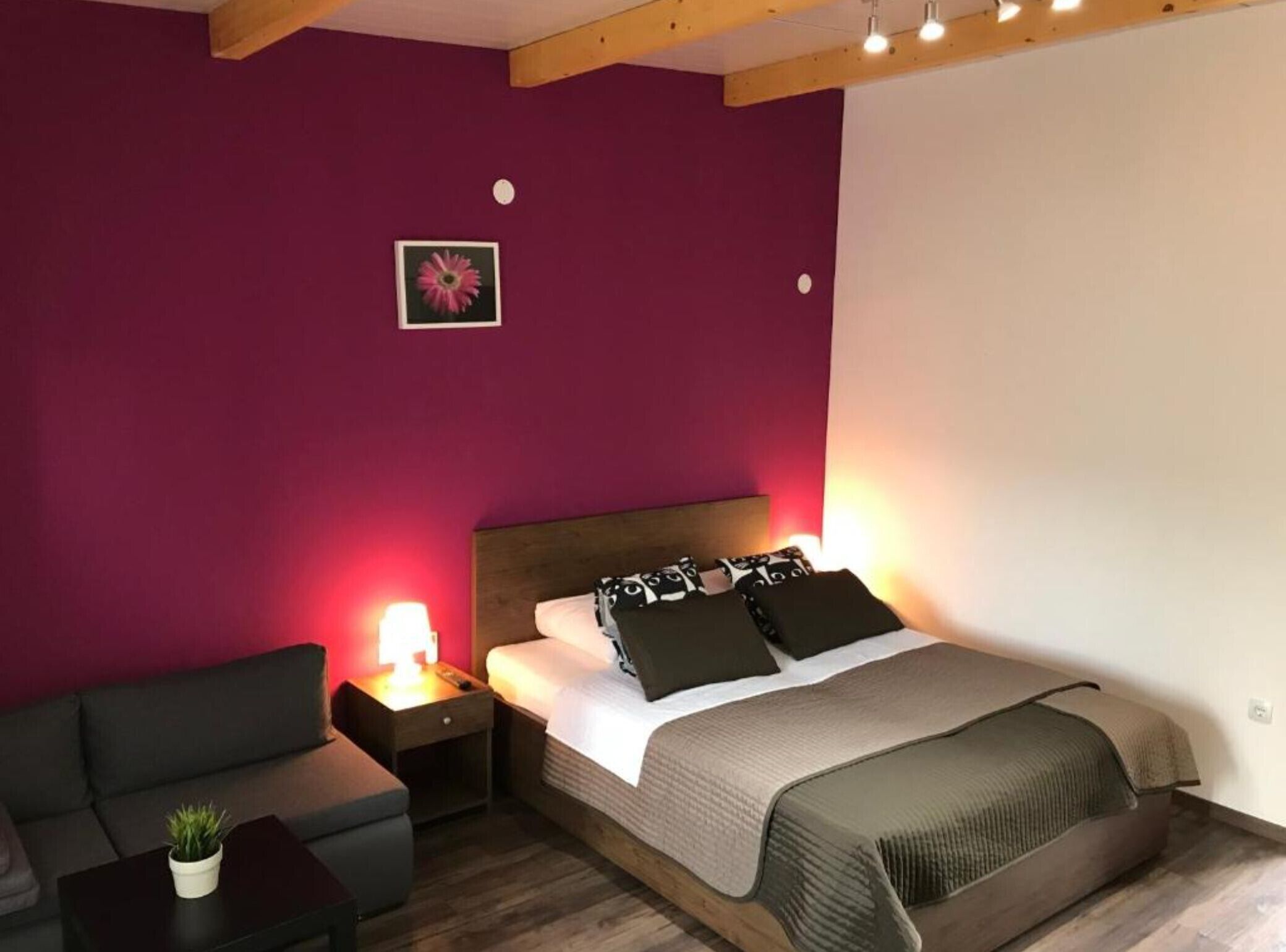 Een slaapkamer met een bed, nachtkastje, lamp, bank en een kleine plant.