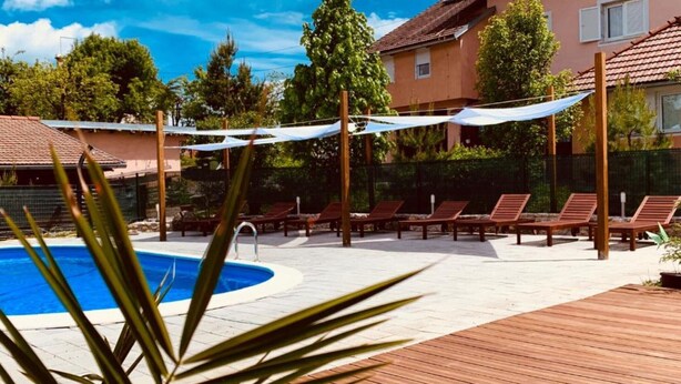 A pool area with lounge chairs and a wooden deck. - One bedroom apartment (Rakovica)