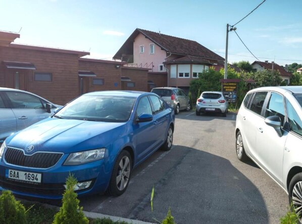 Un estacionamiento con varios coches, incluyendo un sedán azul y un SUV blanco.