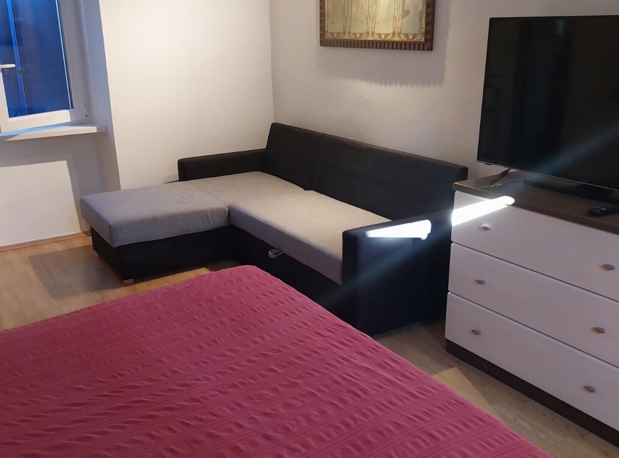 Une chambre comprenant un lit, un canapé-lit, une télévision et une commode.