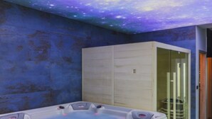 Un spa moderno con techo estrellado, una bañera de hidromasaje y un armario de madera.