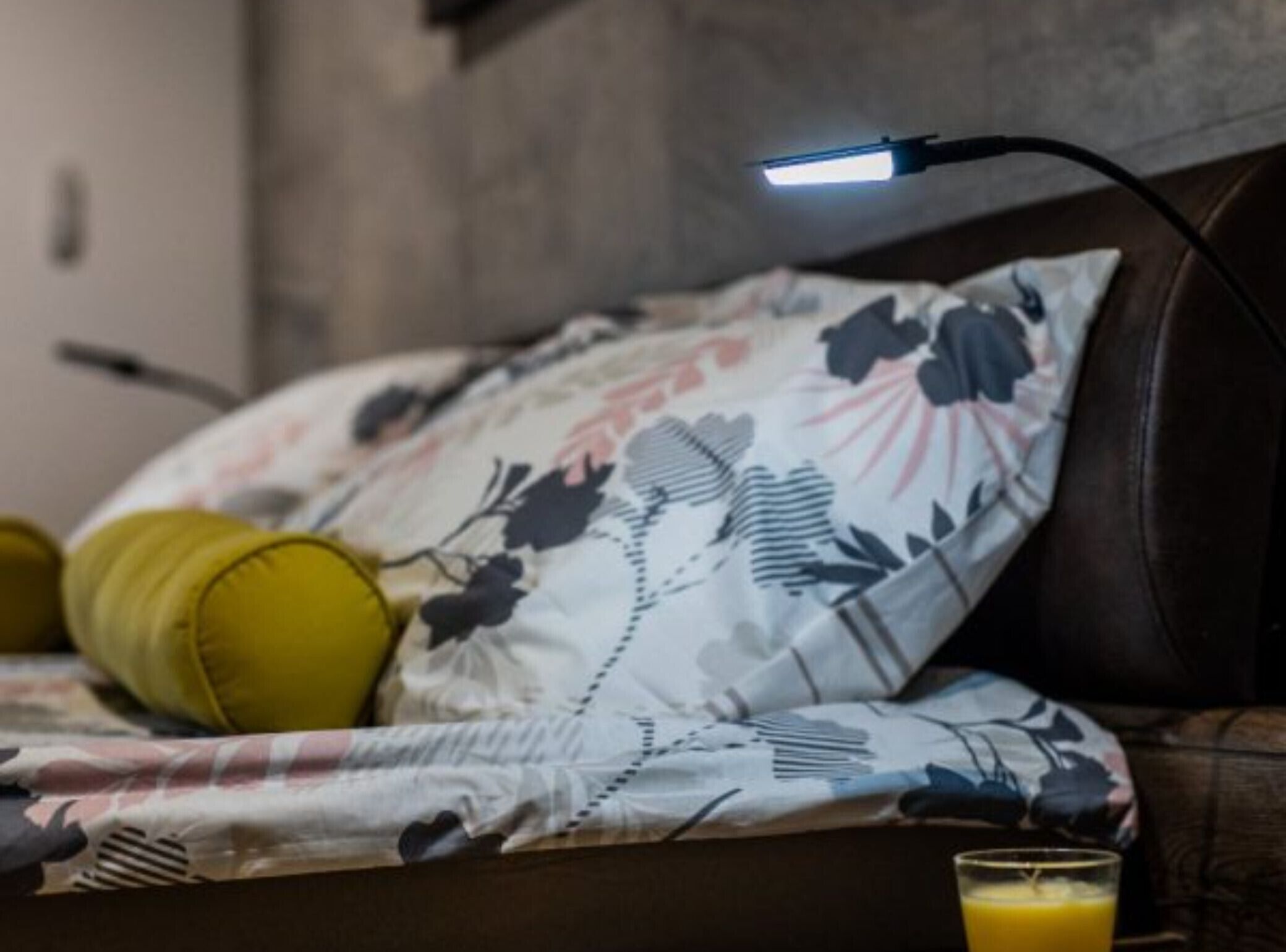 Un lit avec une literie à motifs floraux et une lampe de chevet.