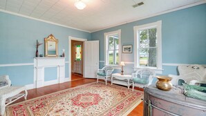 A room with a blue wall, white trim, a patterned rug, wicker chairs, a fireplace, and a window. - Spacious Owensville Getaway w/ Winery On-Site! (Owensville)