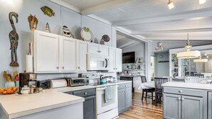 Une cuisine moderne avec des meubles blancs, un îlot central, un four à micro-ondes et une cuisinière.
