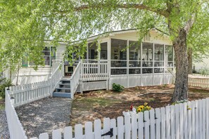 A house with a covered porch, a white fence, and a tree. - Lake Marion Canal Home: Dock, Yard, Porch (Summerton)