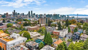 A cityscape with a mix of residential and commercial buildings, including a prominent tower and a bridge in the distance. - Highgarden The Tyrell House Sweet Suite (Seattle)