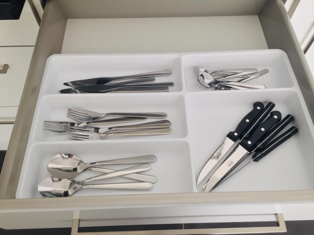 A drawer with compartments containing various kitchen utensils.