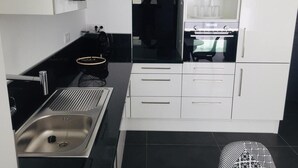 Una cocina moderna con armarios blancos, un refrigerador negro y un lavamanos de acero inoxidable.