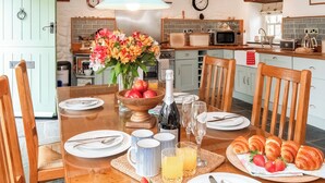 A dining table set with plates, cutlery, a bottle of champagne, glasses, and a bowl of strawberries. - 3 bedroom accommodation in Mathry, nr St Davids (Mathry, nr St Davids)